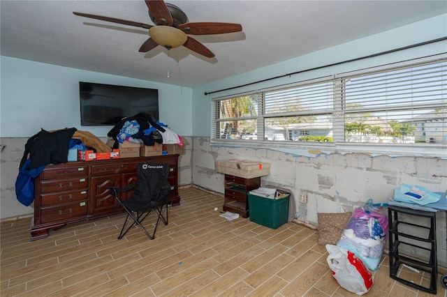 interior space with a textured ceiling, ceiling fan, and wood tiled floor