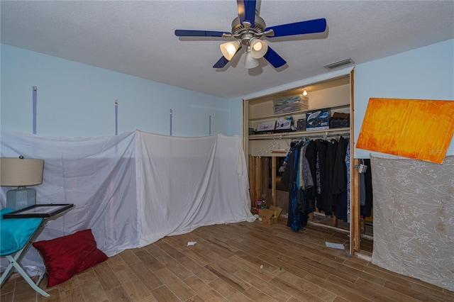 bedroom with visible vents, ceiling fan, wood tiled floor, a closet, and a textured ceiling