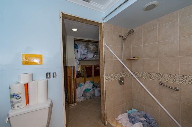 bathroom featuring toilet, tile patterned flooring, and a tile shower