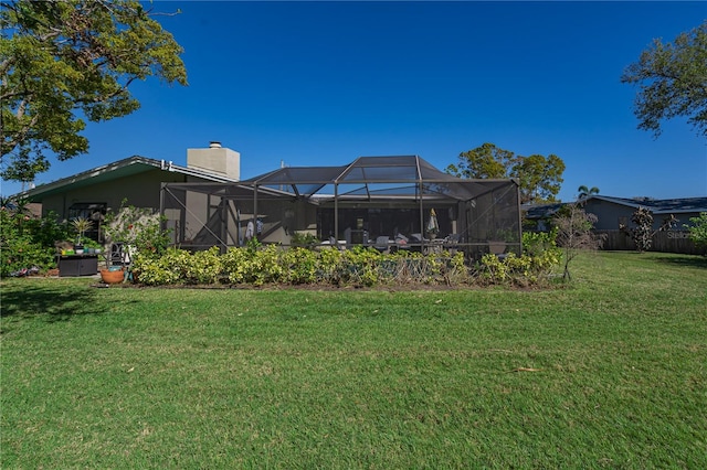 back of property featuring a lanai, a yard, and a chimney