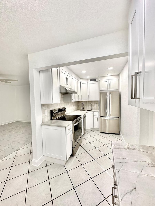 kitchen with stainless steel appliances, light countertops, under cabinet range hood, white cabinetry, and tasteful backsplash