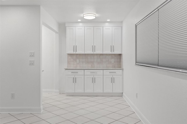 209 NE Lincoln Cir N Unit 105, Saint Petersburg, FL 33702 - kitchen with tasteful backsplash, light countertops, white cabinetry, light tile patterned floors, and baseboards
