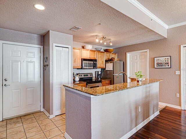 kitchen with stone counters, a textured ceiling, visible vents, and stainless steel appliances