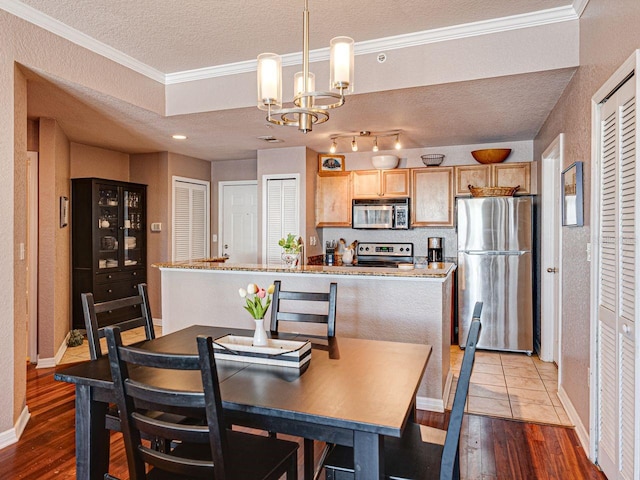 dining room with a textured ceiling, wood finished floors, a notable chandelier, and ornamental molding