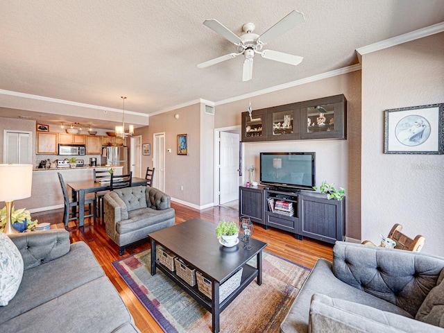 living area with a textured ceiling, light wood-style floors, ornamental molding, and ceiling fan with notable chandelier