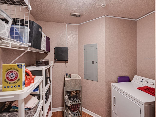 washroom featuring electric panel, washer / clothes dryer, wood finished floors, laundry area, and a textured wall