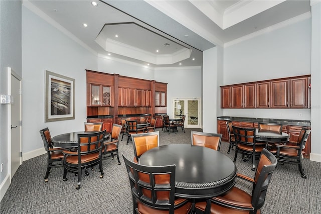 carpeted dining area with recessed lighting, ornamental molding, baseboards, a raised ceiling, and a towering ceiling
