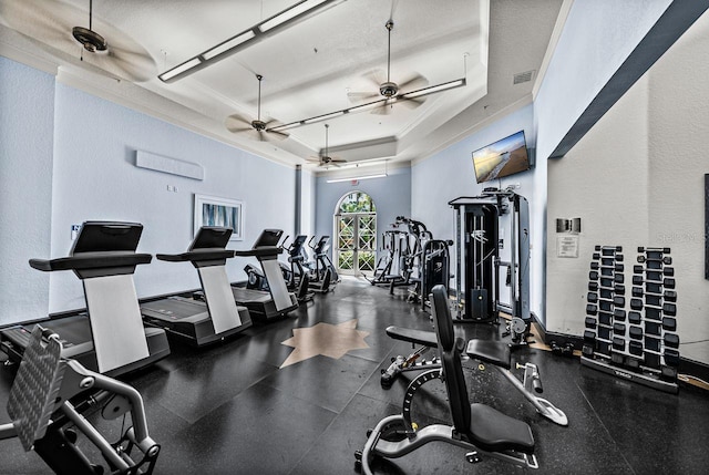 gym featuring a tray ceiling, visible vents, ceiling fan, and ornamental molding