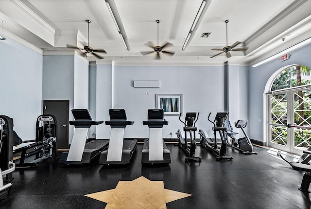 workout area featuring a raised ceiling, a ceiling fan, baseboards, visible vents, and ornamental molding