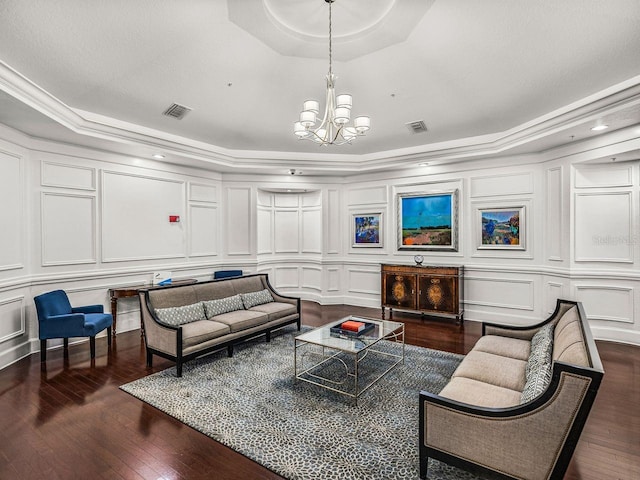 living area featuring an inviting chandelier, a decorative wall, a tray ceiling, and visible vents