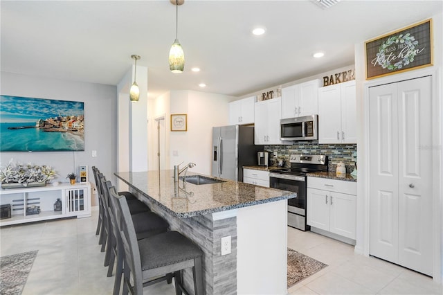 kitchen featuring backsplash, appliances with stainless steel finishes, light tile patterned flooring, a sink, and dark stone countertops