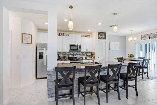 kitchen featuring stainless steel appliances, white cabinetry, a kitchen bar, and tasteful backsplash