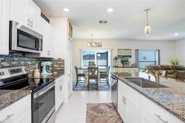 kitchen featuring light tile patterned floors, stainless steel appliances, a sink, visible vents, and tasteful backsplash