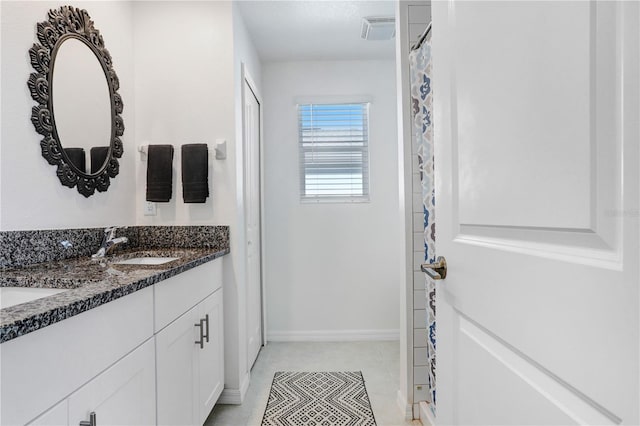 full bath with double vanity, a sink, visible vents, and baseboards