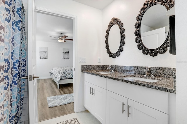 full bathroom with a ceiling fan, double vanity, a sink, and wood finished floors