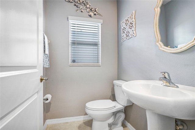 bathroom with toilet, tile patterned flooring, baseboards, and a sink