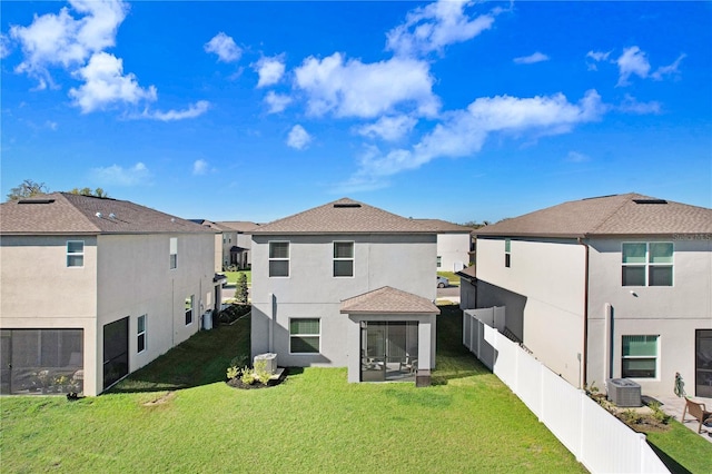 rear view of property with a yard, stucco siding, central AC, fence private yard, and a residential view