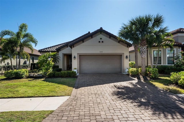 mediterranean / spanish-style home featuring stucco siding, an attached garage, decorative driveway, and a front lawn