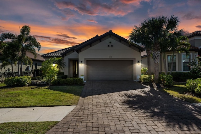 view of front facade featuring stucco siding, an attached garage, decorative driveway, and a yard