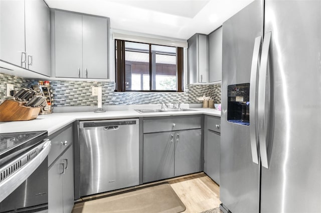 kitchen with appliances with stainless steel finishes, a sink, and gray cabinetry