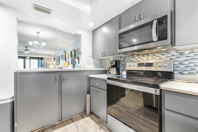 kitchen with appliances with stainless steel finishes, backsplash, gray cabinets, and visible vents