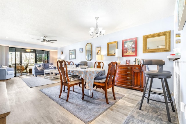 dining area featuring a textured ceiling, ceiling fan with notable chandelier, and wood finished floors