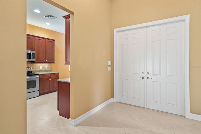 kitchen featuring visible vents, backsplash, light stone counters, light tile patterned flooring, and stainless steel appliances