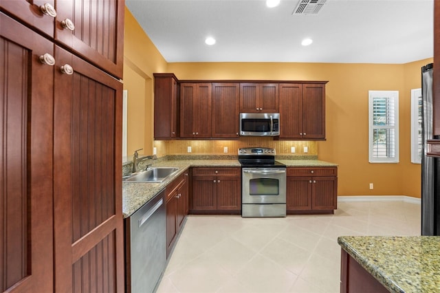 kitchen featuring light stone counters, visible vents, a sink, decorative backsplash, and appliances with stainless steel finishes