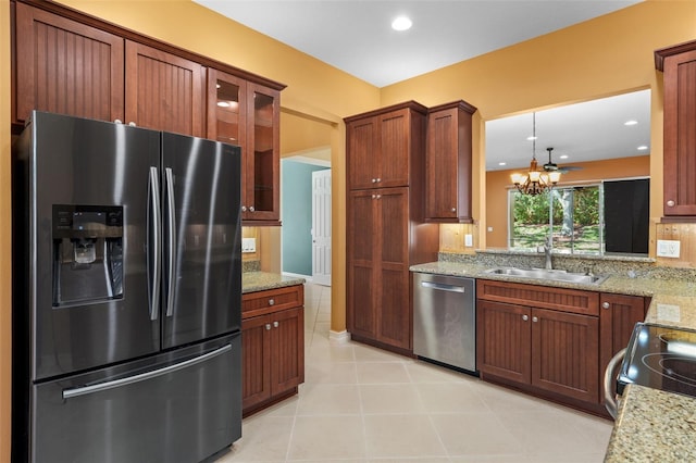 kitchen featuring light stone counters, a sink, glass insert cabinets, appliances with stainless steel finishes, and a notable chandelier