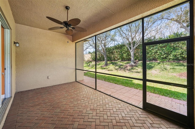 unfurnished sunroom with ceiling fan