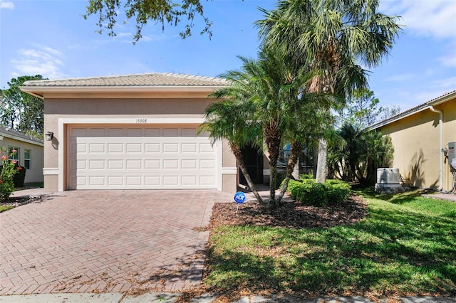 view of front of house with a front yard, a tiled roof, decorative driveway, and stucco siding