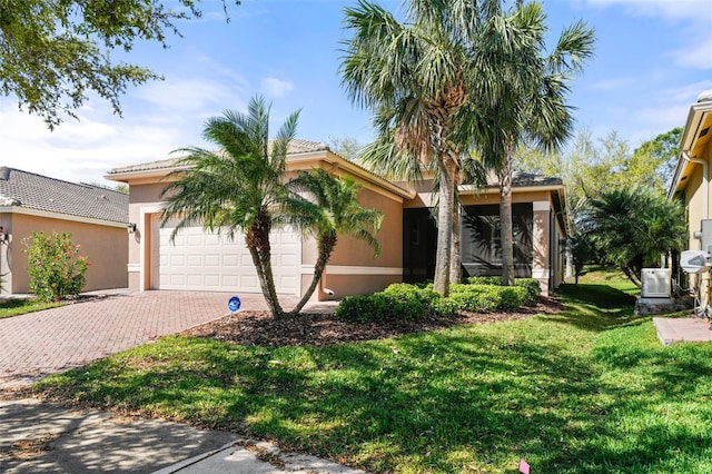 view of front of property featuring a front lawn, a tile roof, stucco siding, decorative driveway, and a garage