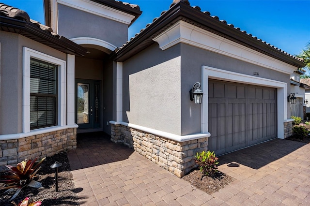 exterior space with stucco siding, stone siding, and a garage