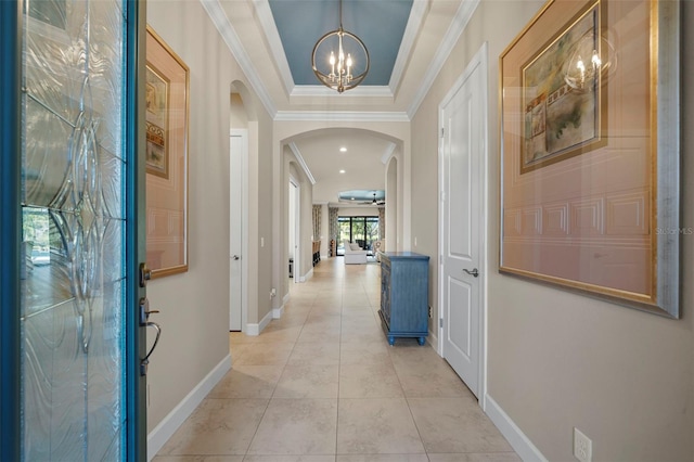 entrance foyer featuring light tile patterned floors, baseboards, arched walkways, crown molding, and ceiling fan with notable chandelier