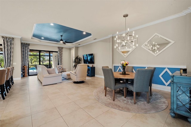 dining area featuring tile patterned floors, a raised ceiling, ceiling fan with notable chandelier, crown molding, and baseboards