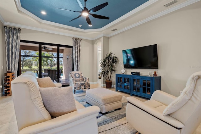 living area featuring tile patterned flooring, visible vents, a raised ceiling, and ceiling fan