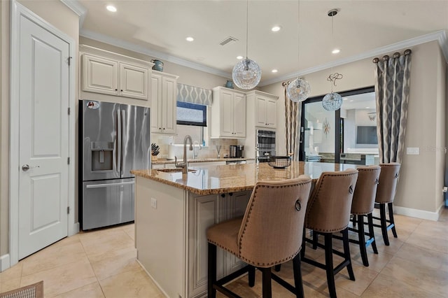 kitchen with visible vents, stainless steel appliances, an island with sink, and ornamental molding