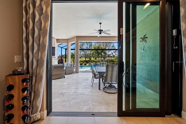 doorway with ceiling fan, a sunroom, and a textured ceiling