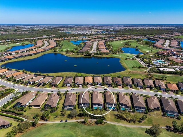 drone / aerial view with golf course view, a residential view, and a water view