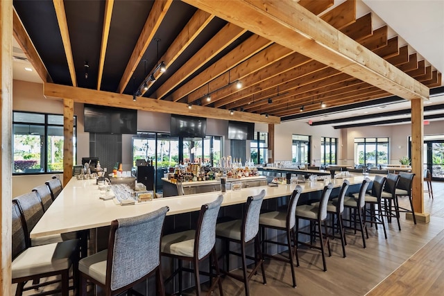 bar featuring light wood-type flooring, beam ceiling, and track lighting