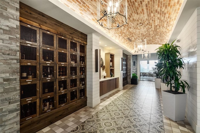 wine cellar with brick ceiling, a chandelier, and vaulted ceiling