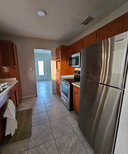 kitchen with brown cabinetry, visible vents, stainless steel appliances, and light countertops