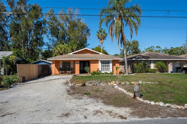 single story home with stucco siding, driveway, a front lawn, and fence