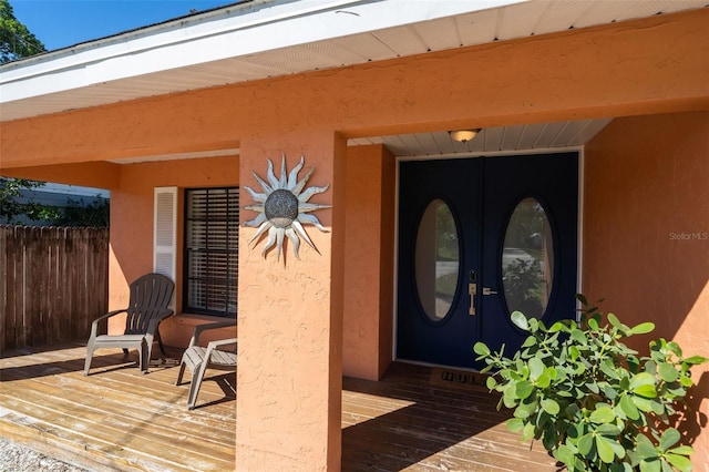 property entrance featuring fence, french doors, and stucco siding