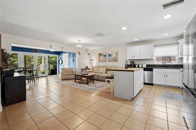 kitchen with light tile patterned floors, open floor plan, visible vents, and stainless steel dishwasher