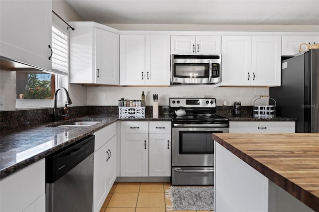 kitchen with white cabinetry, appliances with stainless steel finishes, butcher block counters, and a sink