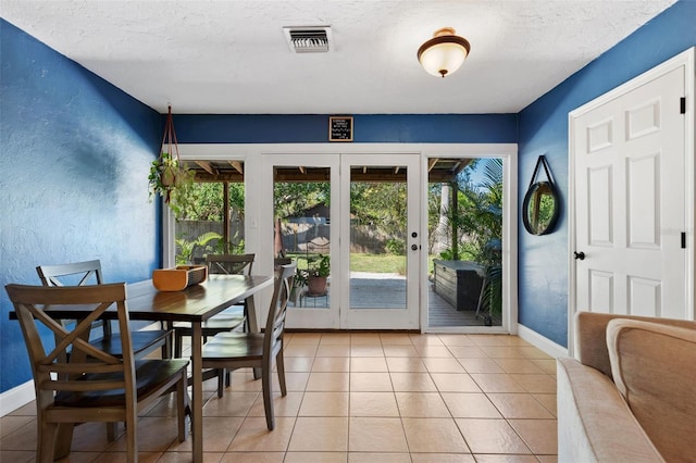 dining area featuring visible vents, baseboards, light tile patterned floors, a textured wall, and a textured ceiling