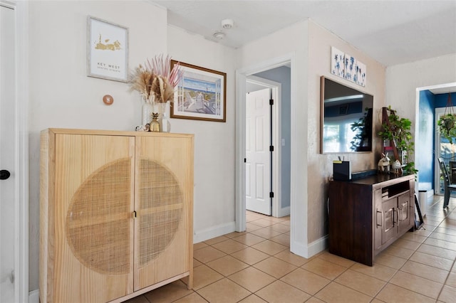 hall featuring light tile patterned floors and baseboards