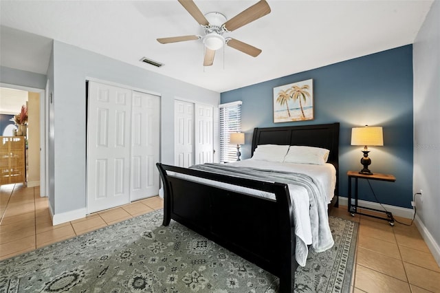 bedroom with light tile patterned floors, visible vents, multiple closets, and baseboards