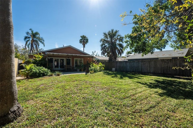 view of yard with a fenced backyard and french doors